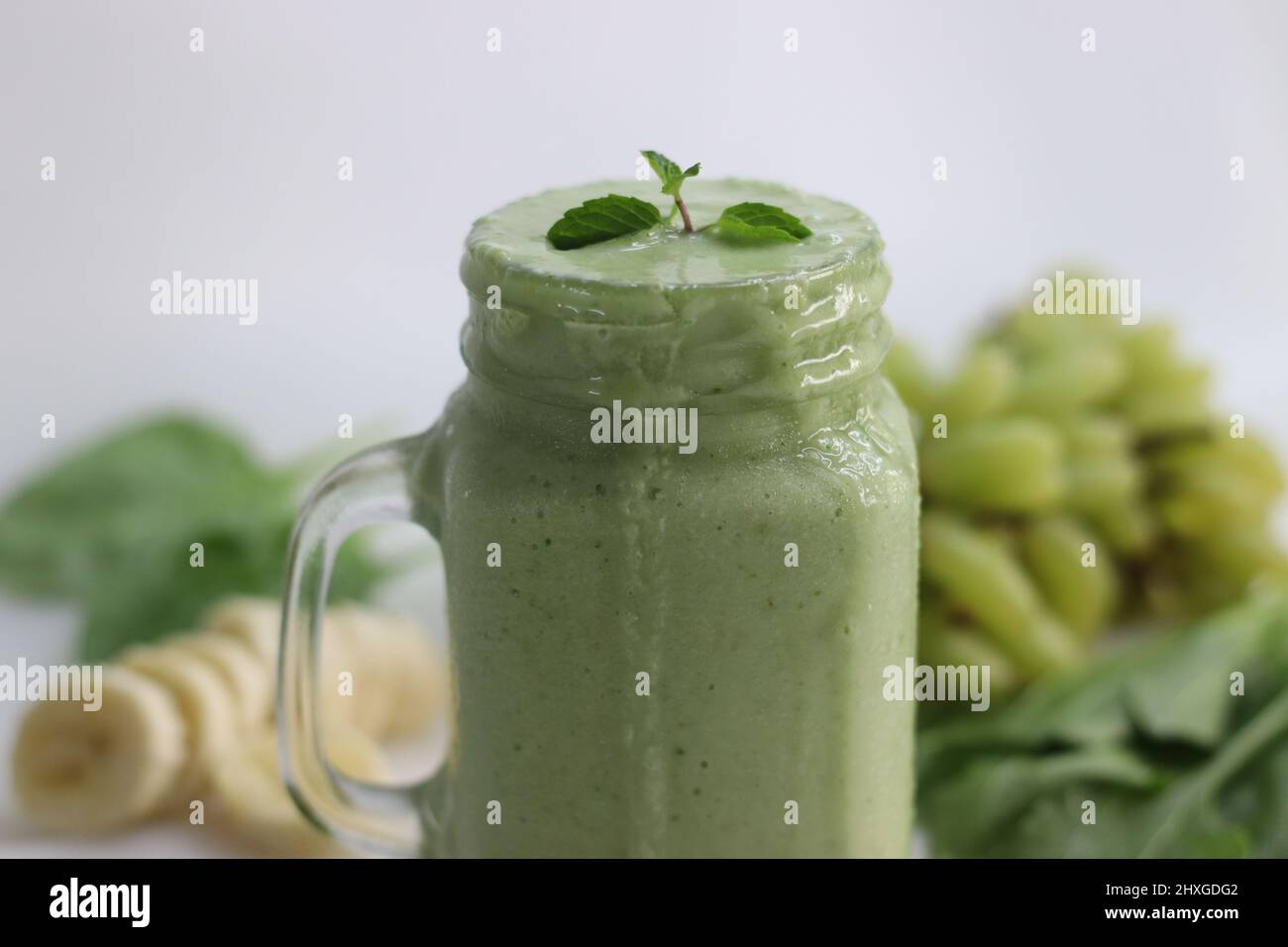 Grüner Smoothie aus gefrorenen grünen Trauben, frischem Babyspinat, Bananen  und Mandelmilch. Serviert im Einmachglas. Aufgenommen auf weißem  Hintergrund Stockfotografie - Alamy