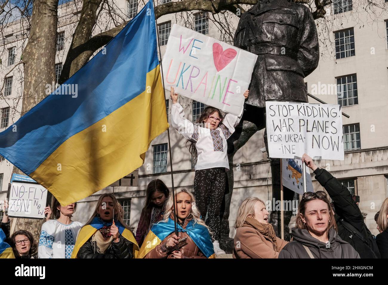 London, 12.. März 2022. Ukrainische Staatsbürger und Anhänger versammeln sich weiterhin in Whitehall gegenüber der Downing Street und fordern mehr Maßnahmen gegen Russland für die Invasion der Ukraine von der internationalen Gemeinschaft. Ein junges Mädchen hält ein Schild mit dem Titel „We Love Ukraine“ über der Menge. Stockfoto