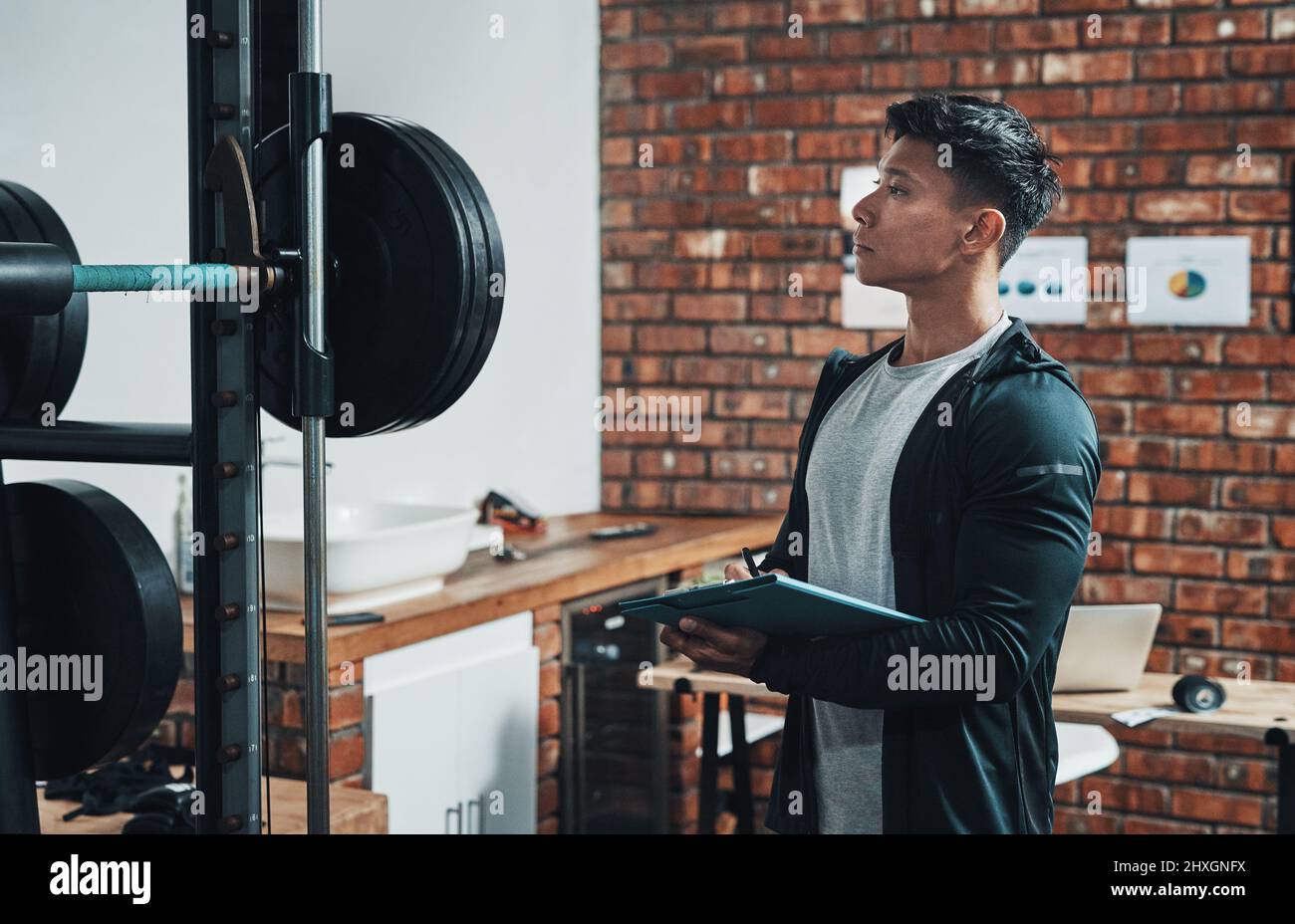 Nur dafür sorgen, dass alles in gutem Zustand ist. Kurzer Schuss eines hübschen jungen männlichen Fitness-Ausbilders, der Trainingsgeräte während der Arbeit in einem inspiziert Stockfoto