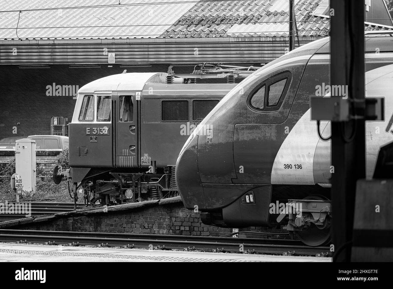 Erhaltene elektrische Lokomotive der Baureihe 86 der 1960er Jahre 86259 in Elektro-Blau und ein moderner Alstom-gebauter Virgin Pendolino-Zug am Bahnhof Preston Stockfoto