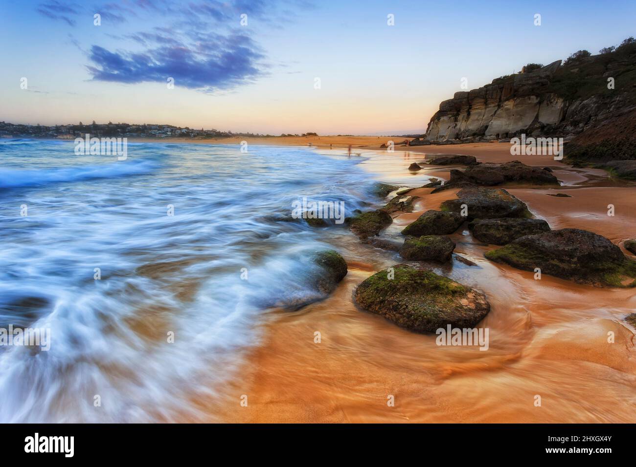 Sand- und wassergespülte Felsbrocken am Curl Curl Beach von Sydney North Shore bei Sonnenaufgang - malerische Küste. Stockfoto