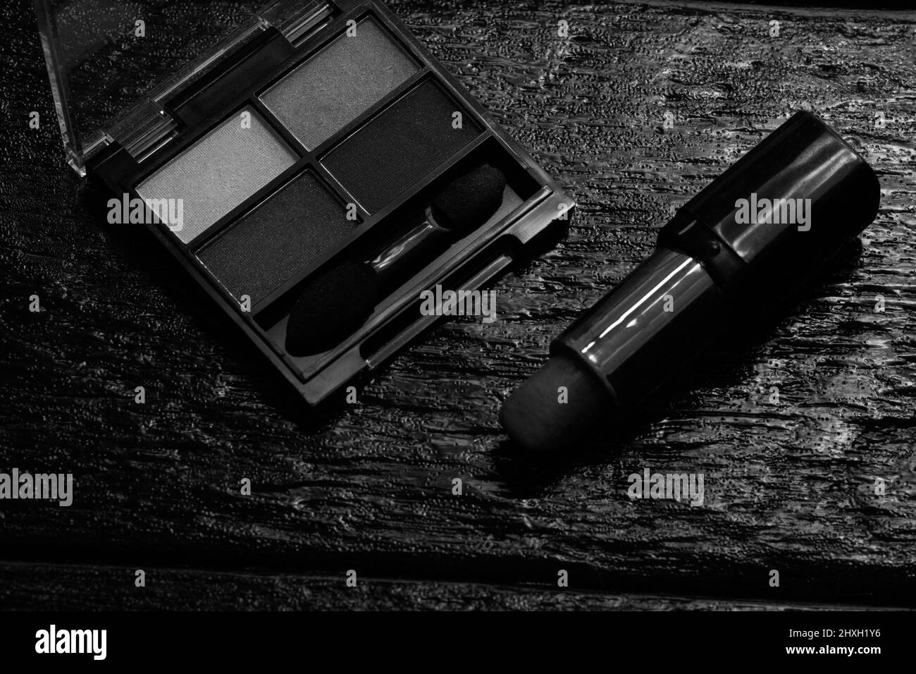 Kosmetik auf einem schwarzen, Nagellack, Lidschatten-Palette, Lippenstift, Pinsel, Parfume Stockfoto