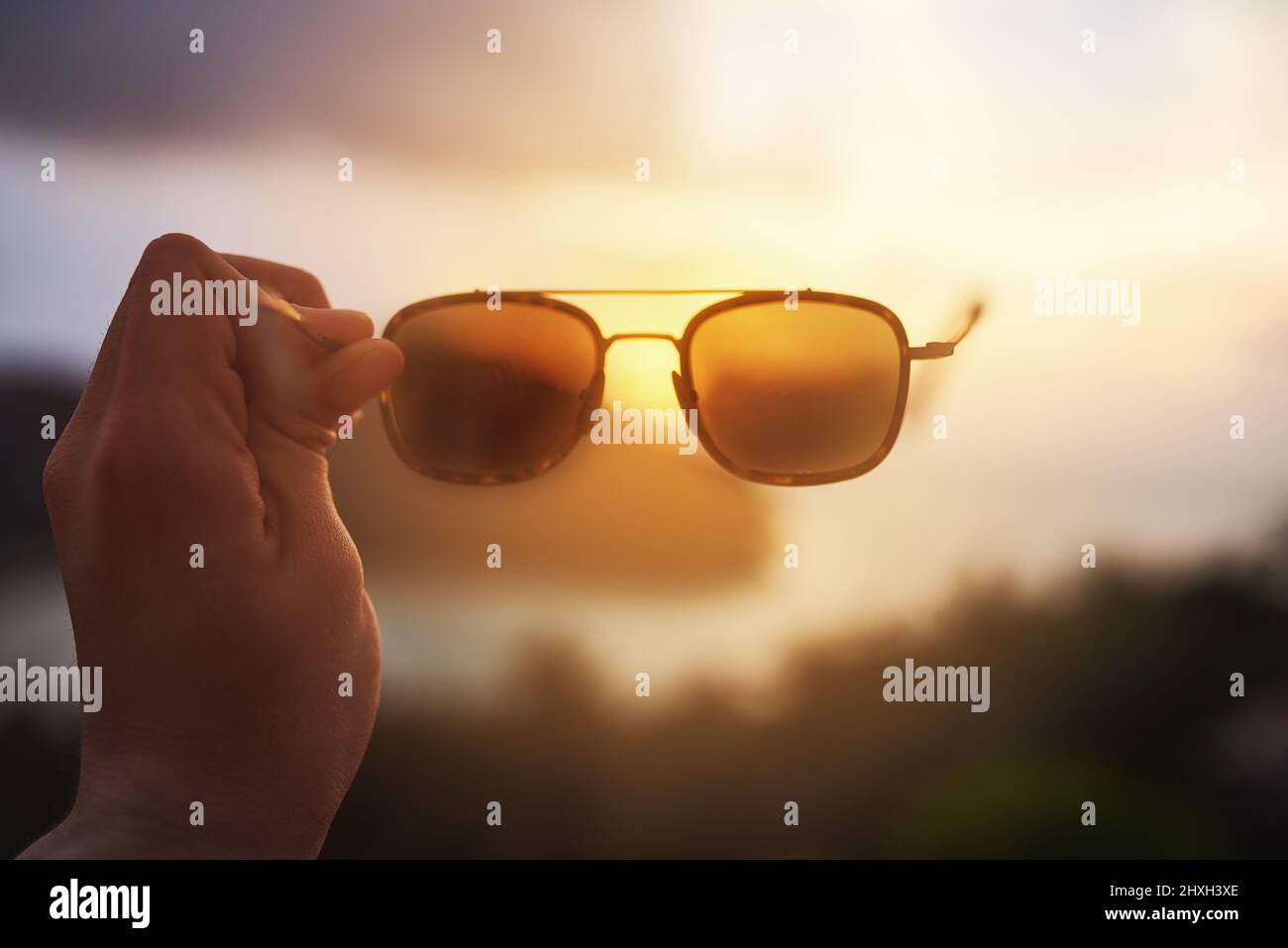 Leben durch rosafarbene Gläser. Eine kurze Aufnahme eines nicht identifizierbaren Touristen, der eine Sonnenbrille über einem tropischen Blick hält. Stockfoto