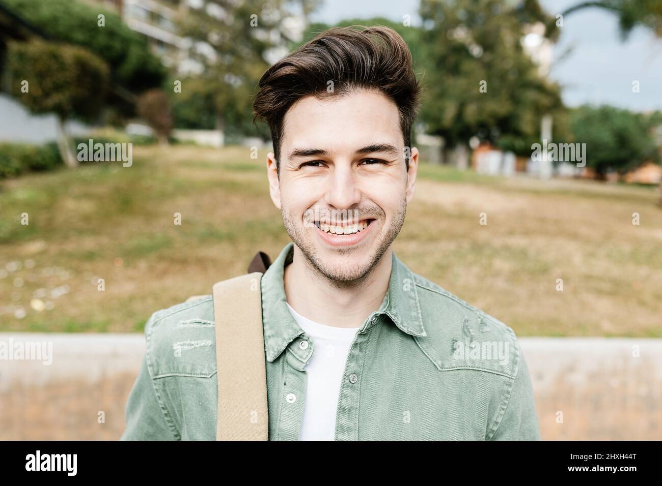 Trendy schöner junger Student Mann mit Rucksack lächelt an der Kamera Stockfoto