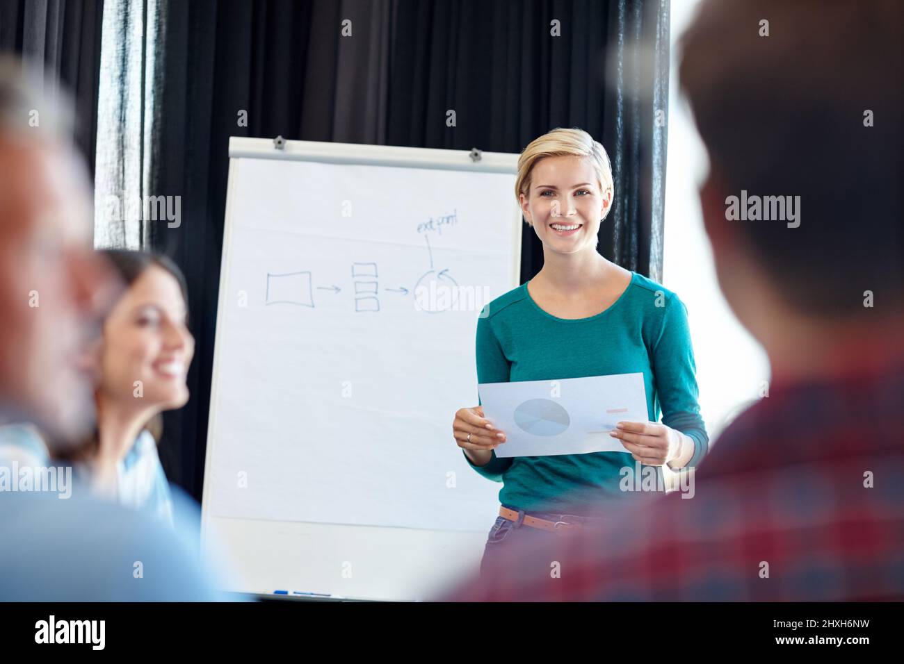 Zeigen Sie ihnen die Wertschätzung der Mitarbeiter. Aufnahme einer attraktiven Frau, die eine Präsentation für ihre Kollegen macht. Stockfoto