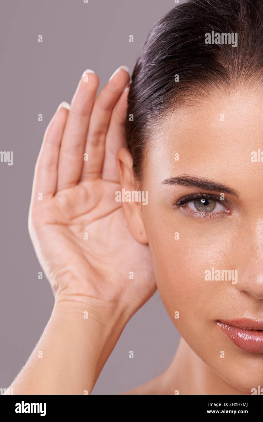 Nehmen Sie Ihren Schönheitsratschlag. Beauty-Aufnahme einer jungen Frau mit einer kuppeligen Hand hinter ihrem Ohr. Stockfoto