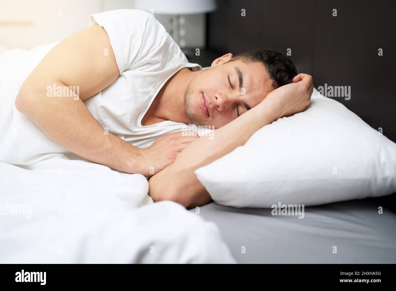 Den ganzen Schlaf zu bekommen, den sein Körper braucht. Kurzer Schuss eines hübschen jungen Mannes, der im Alter von bed0 schläft. Stockfoto