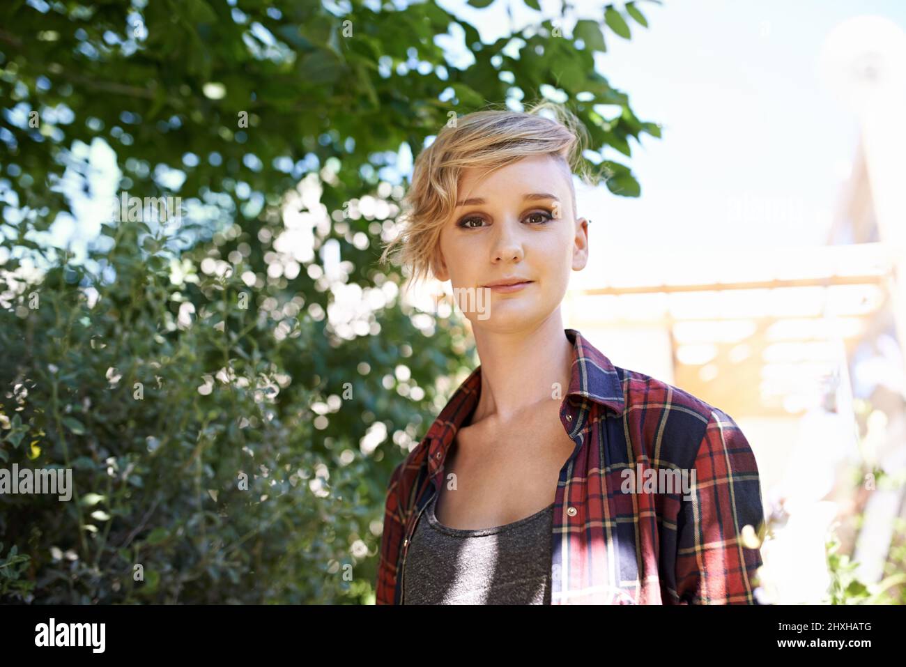 Ich liebe meinen Garten an einem sonnigen Tag. Ein beschnittenes Porträt einer schönen jungen Frau, die in ihrem Garten steht. Stockfoto