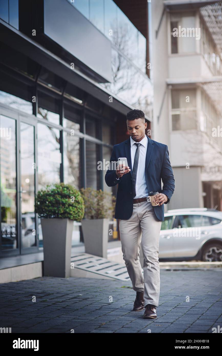 Bevor es zurück geht, einen schnellen Kaffee zu sich nehmen. Aufnahme eines hübschen jungen Geschäftsmannes, der in der Stadt ein Mobiltelefon benutzt. Stockfoto