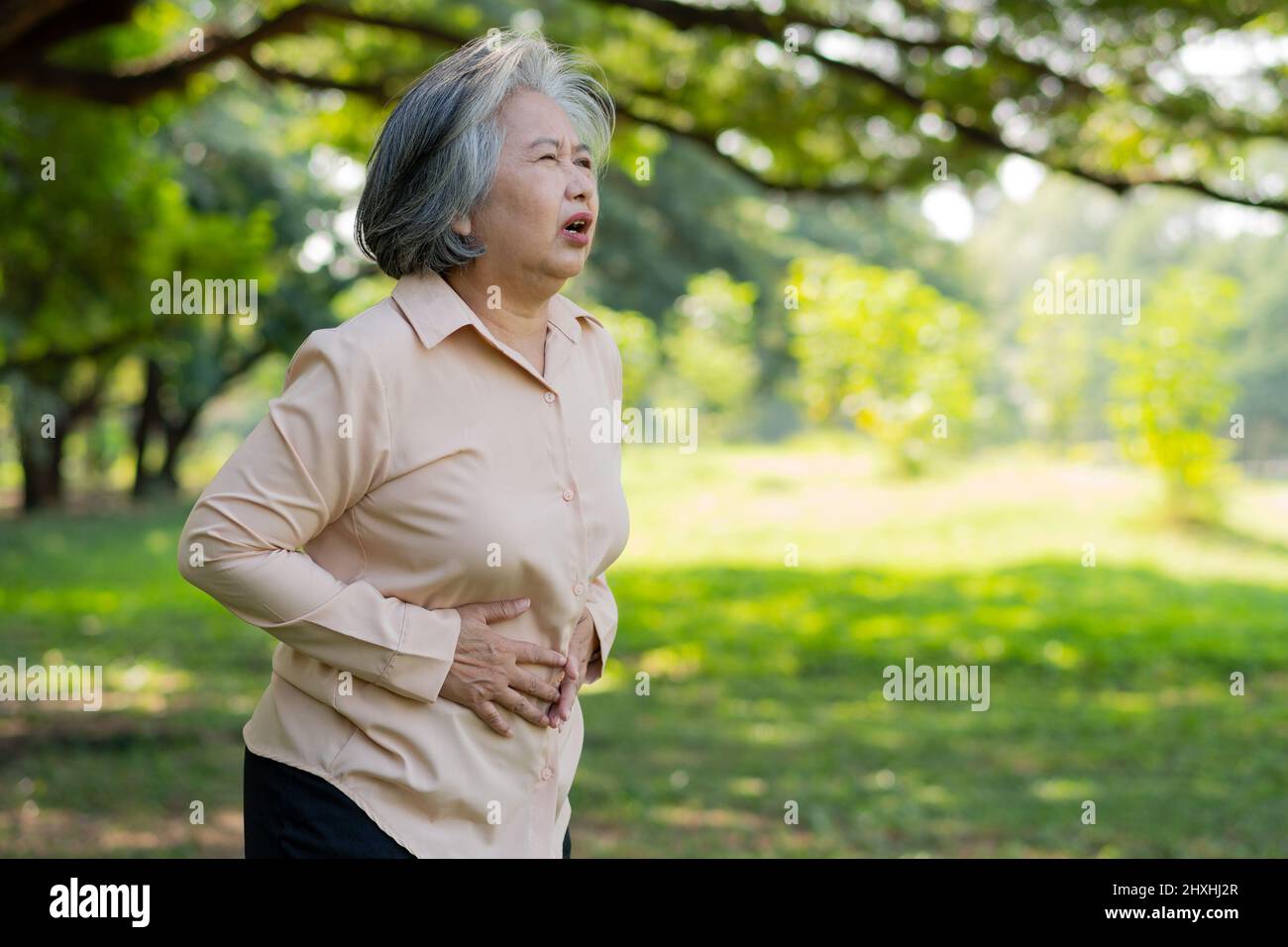 Kranke asiatische ältere Frau Magenschmerzen oder Gastroenterologen, ältere Menschen haben ein Magenproblem, akute Pankreatitis verursachen Magenschmerzen, Symptome Gastroint Stockfoto