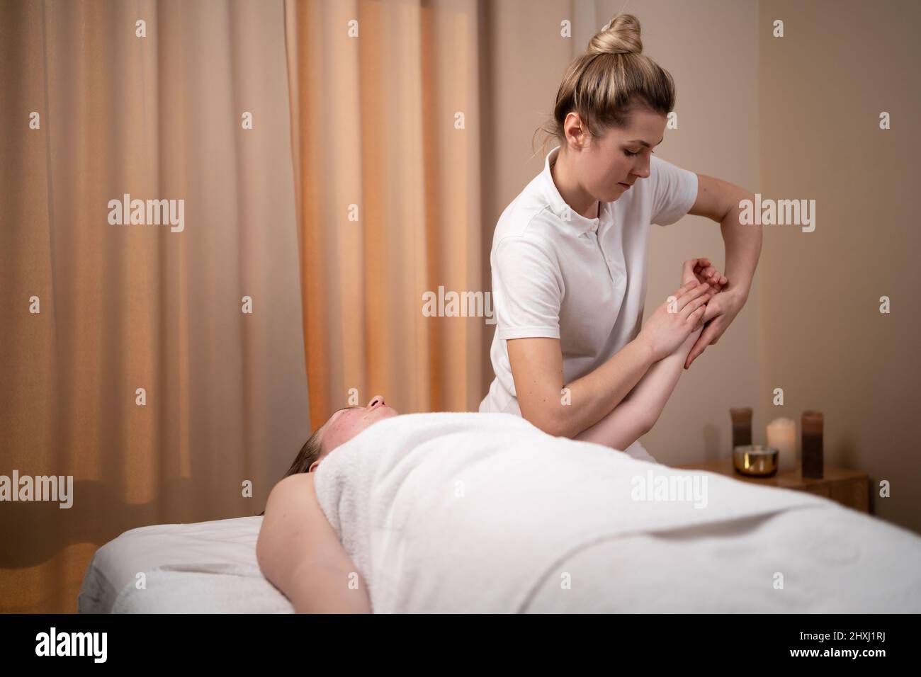 Die junge Frau erhält eine Handmassage im Wellnesscenter. Eine Patientin wird von einem Ergotherapeuten behandelt. Stockfoto
