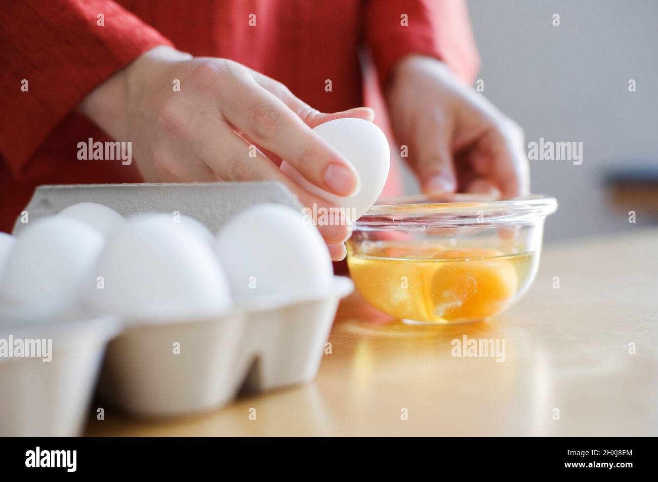 Zubereitung von Speisen, Hände, die ein rohes Ei aufbrechen. Stockfoto
