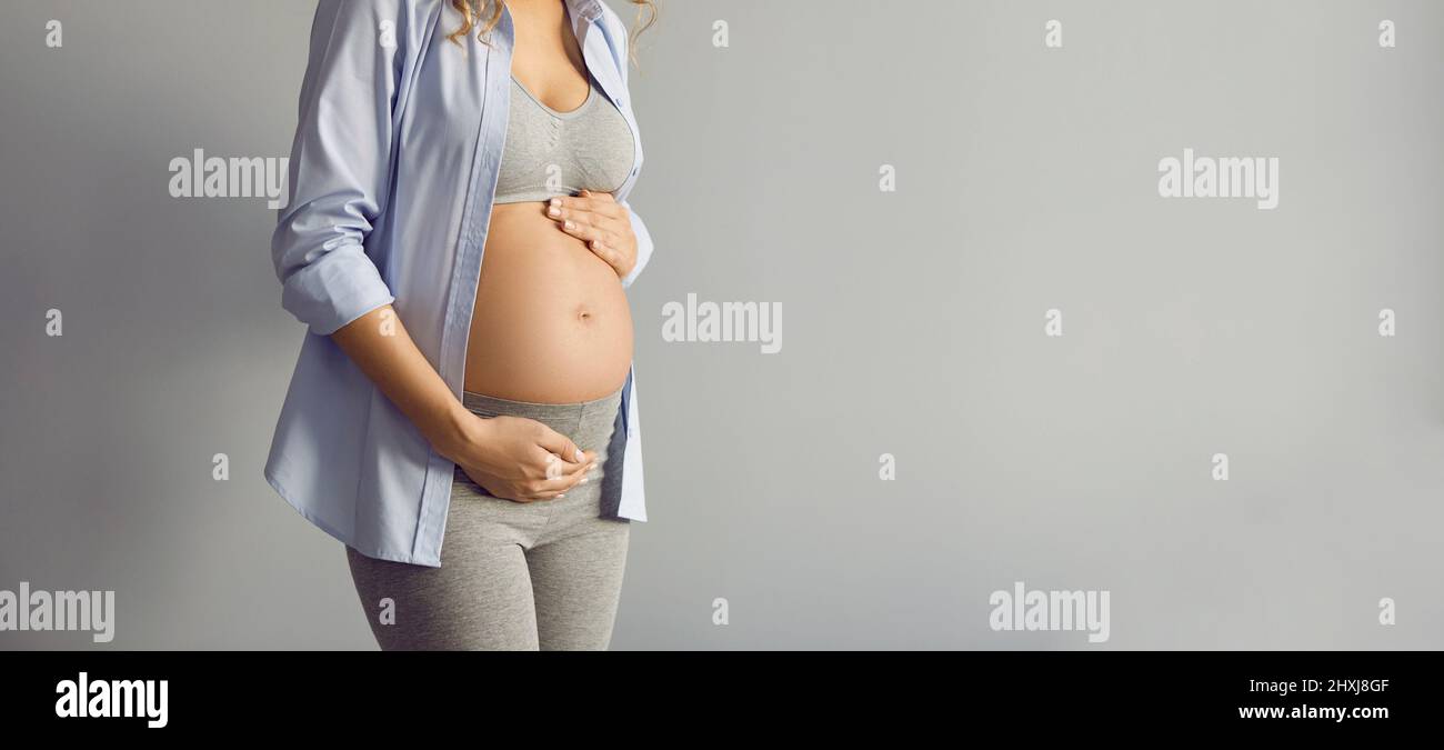 Kopieren Sie Space Banner Hintergrund mit einer Schwangeren Dame im Studio stehen und berühren ihren Bauch Stockfoto