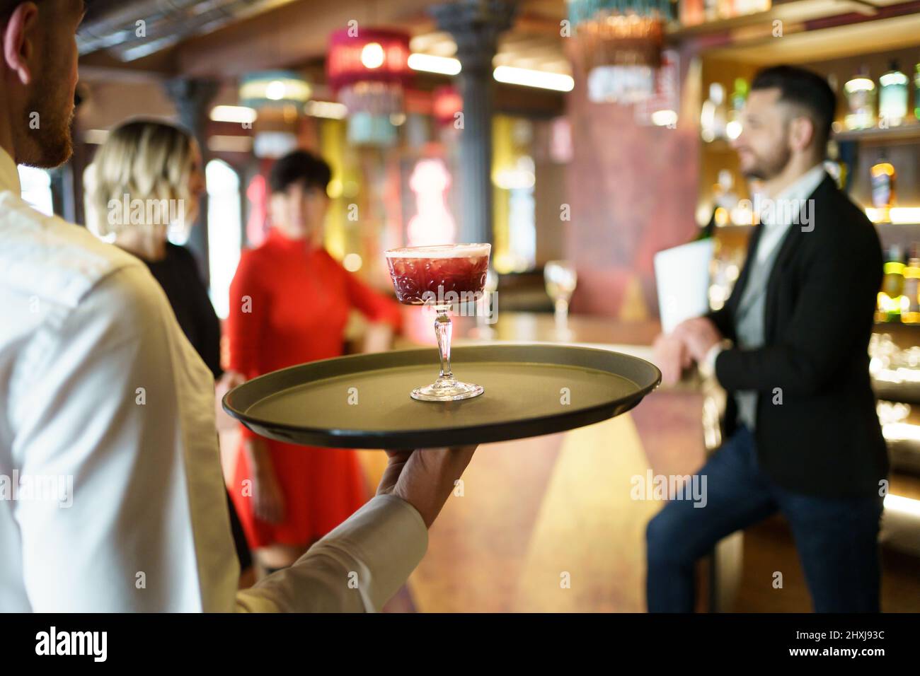 Kellner serviert einen Cocktail für elegante Gäste in einer schönen Bar Stockfoto