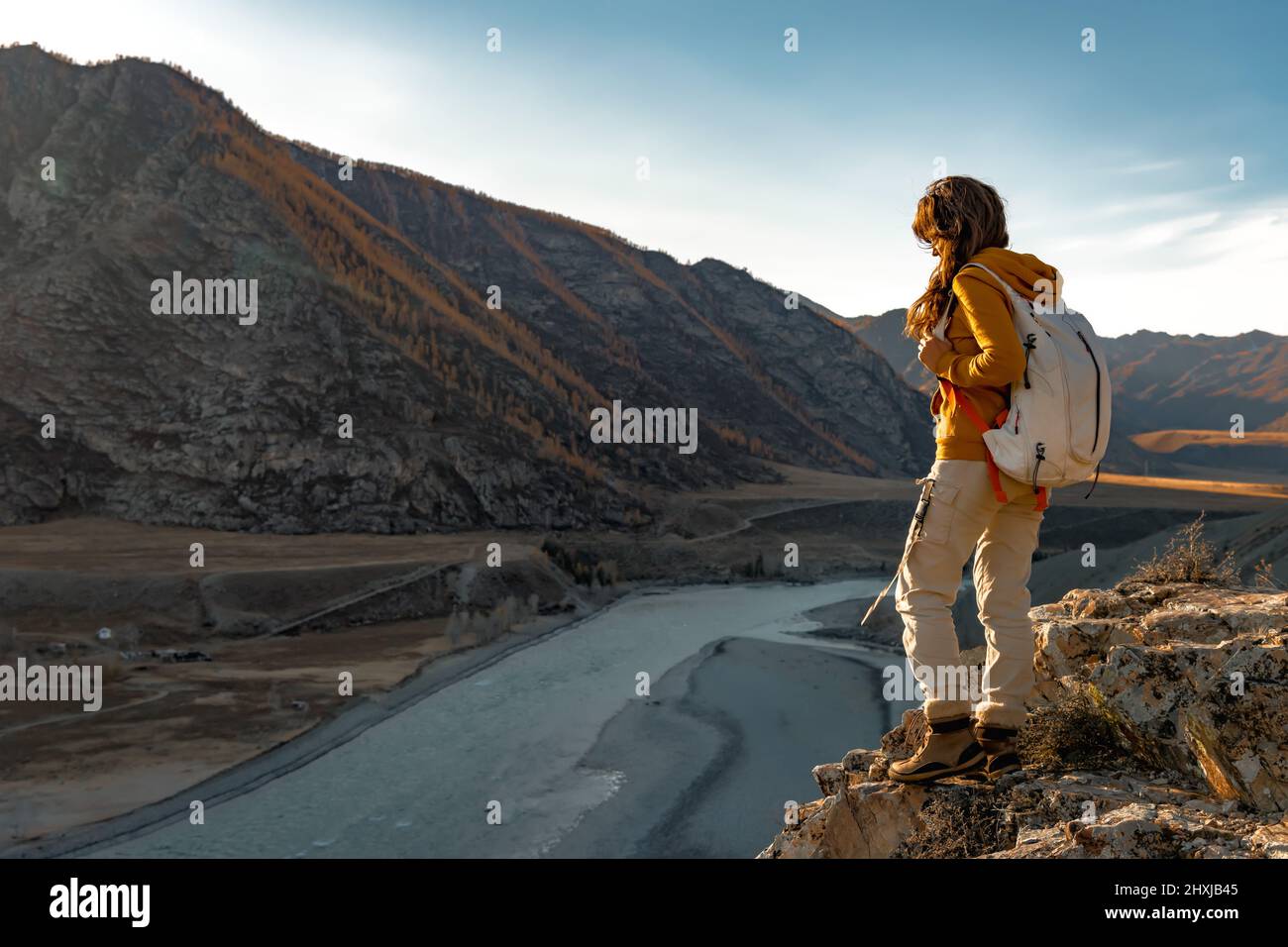 Mädchen Wanderer mit Rucksack steht in den Bergen in der Nähe des Flusses Stockfoto