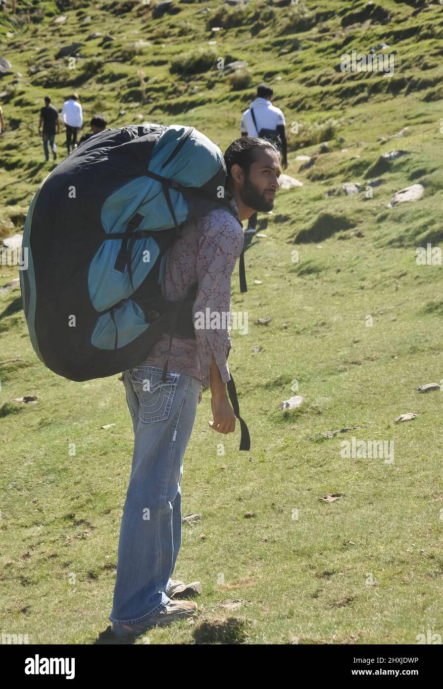 Rückansicht eines männlichen Reisenden, der mit seinen Freunden mit einem Rucksack mit Fallschirm in den Berg läuft Stockfoto
