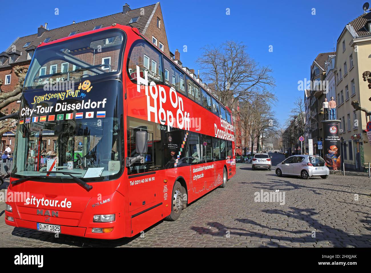 Düsseldorf (Burgplatz), Deutschland - März 9. 2022: Blick auf den Red Hop on and off Sightseeing Bus mit offenem Dach am sonnigen Wintertag, historisches Stadtbild b Stockfoto