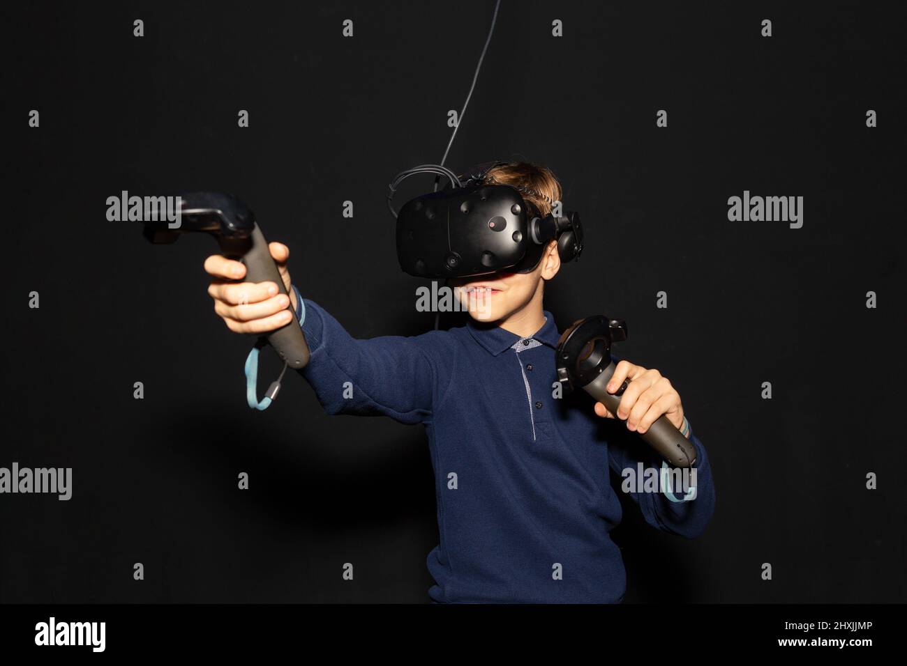 Acht Jahre Junge trägt VR-Headset, hält Controller in den Händen und genießen Sie neue Erfahrung in Videospielen. Schwarzer Hintergrund. Eine Attraktion in einer Ente Stockfoto