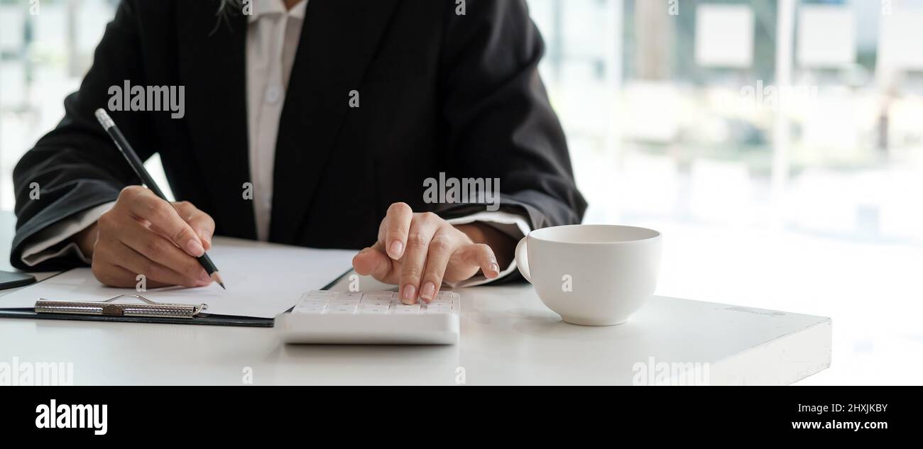 Ausschneiden Schuss der Buchhalterin Frau Handpresse auf Rechner und Schreiben einer Notiz für Finanzbericht oder Unternehmen Gewinn jährlich am Schreibtisch, Buchhalter Job machen Stockfoto