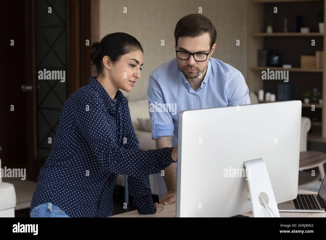 Indische Frau diskutiert Arbeit auf dem pc-Bildschirm mit einem Kollegen Stockfoto
