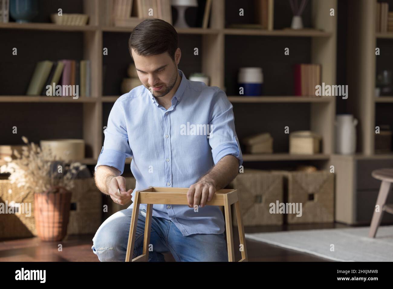 Beschäftigter junger Mann Mann Mann Mann montieren dekorativen Tisch aus Holzteilen Stockfoto