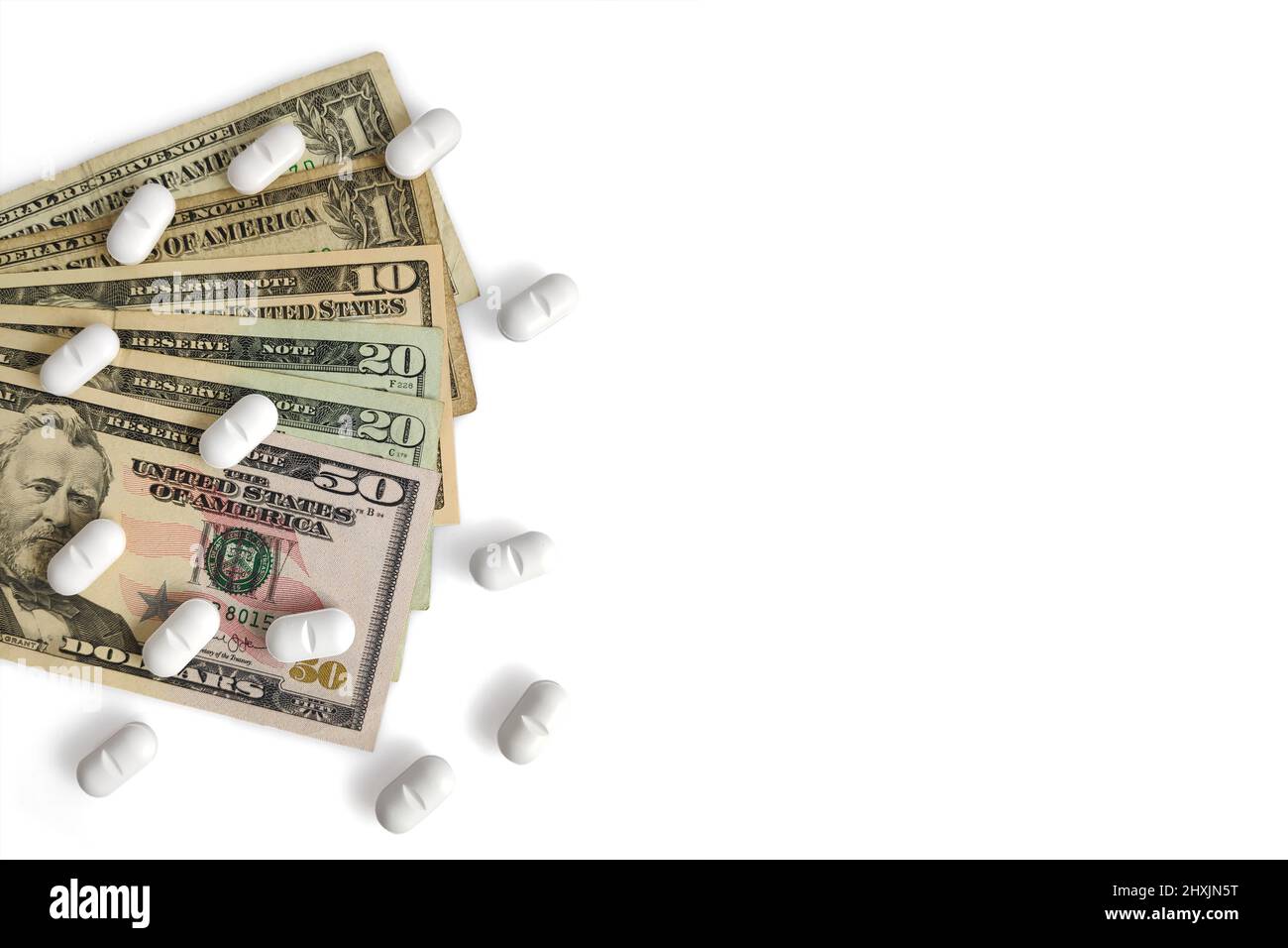 Verstreute pharmazeutische Pillen auf US-Dollar-Banknoten isoliert auf weißem Hintergrund mit Kopieplatz. Stockfoto