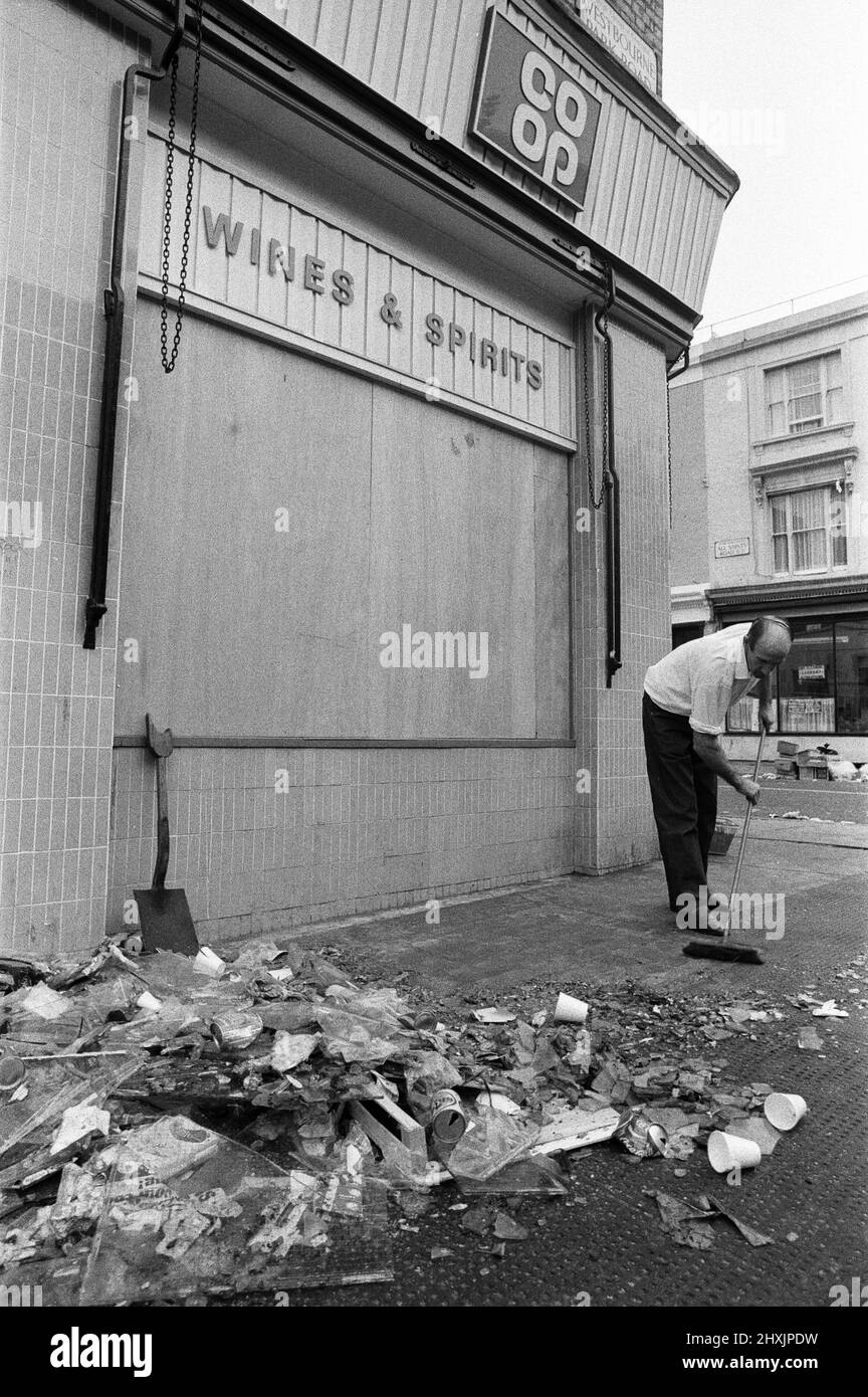 Die Säuberung begann in den Straßen von Notting Hill nach den Unruhen am montagabend nach dem Karneval. Ein Co-Op-Mitarbeiter beginnt die große Aufgabe, den Trümmer zu fegen. 31.. August 1976. Stockfoto