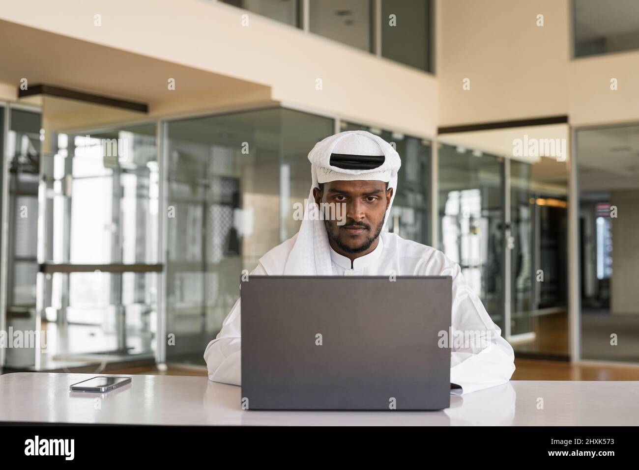Afrikanischer muslimischer Mann, der im Büro einen Laptop benutzt Stockfoto
