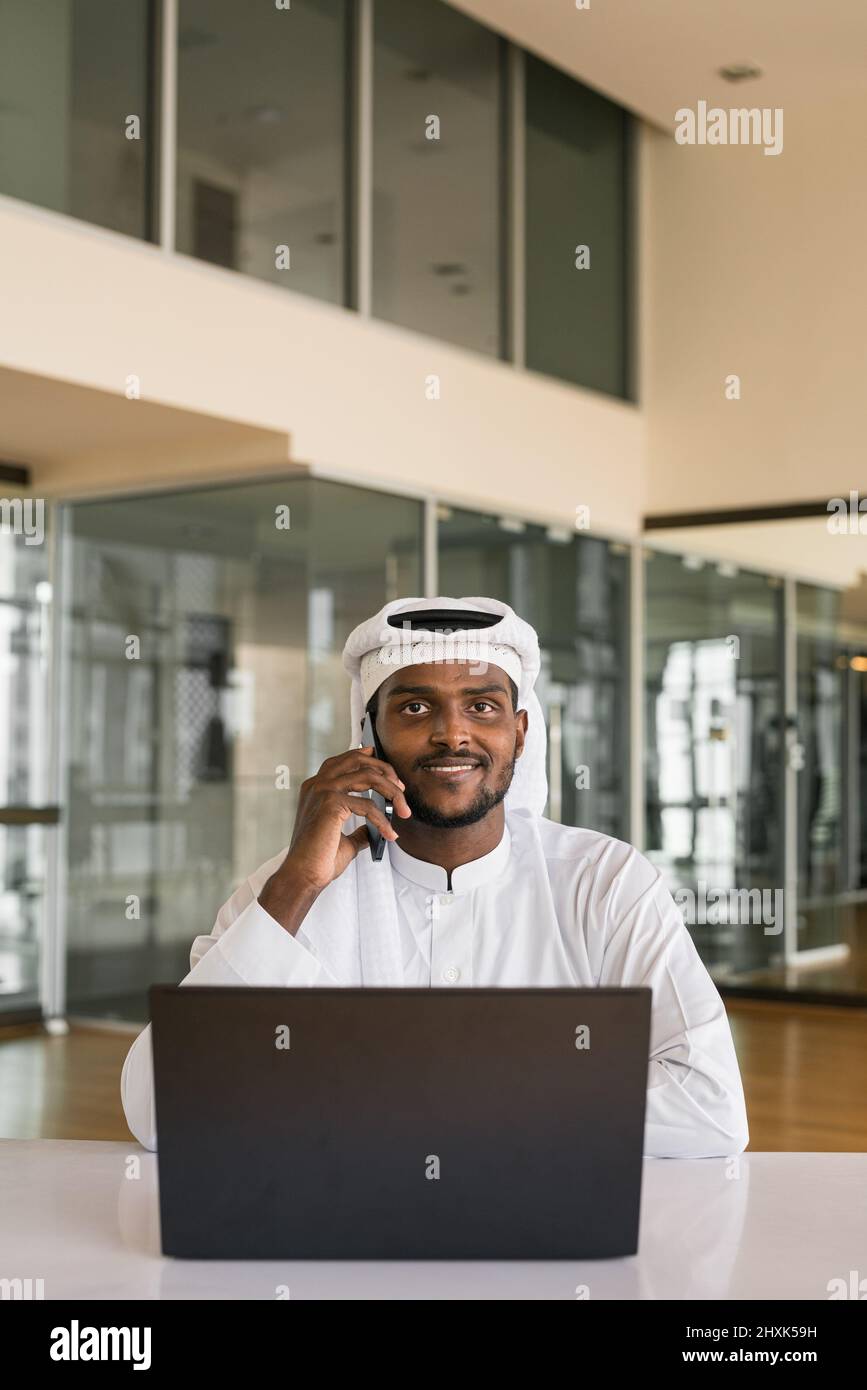 Afrikanischer muslimischer Mann, der im Büro einen Laptop benutzt Stockfoto