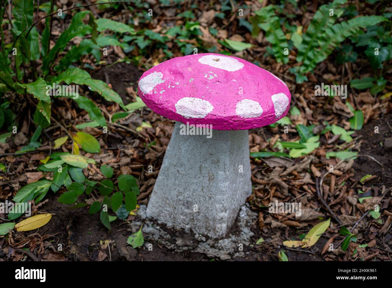 Rosa und weiß bemalter Steinpilzsitz im verzauberten Feengarten im Wald. Stockfoto