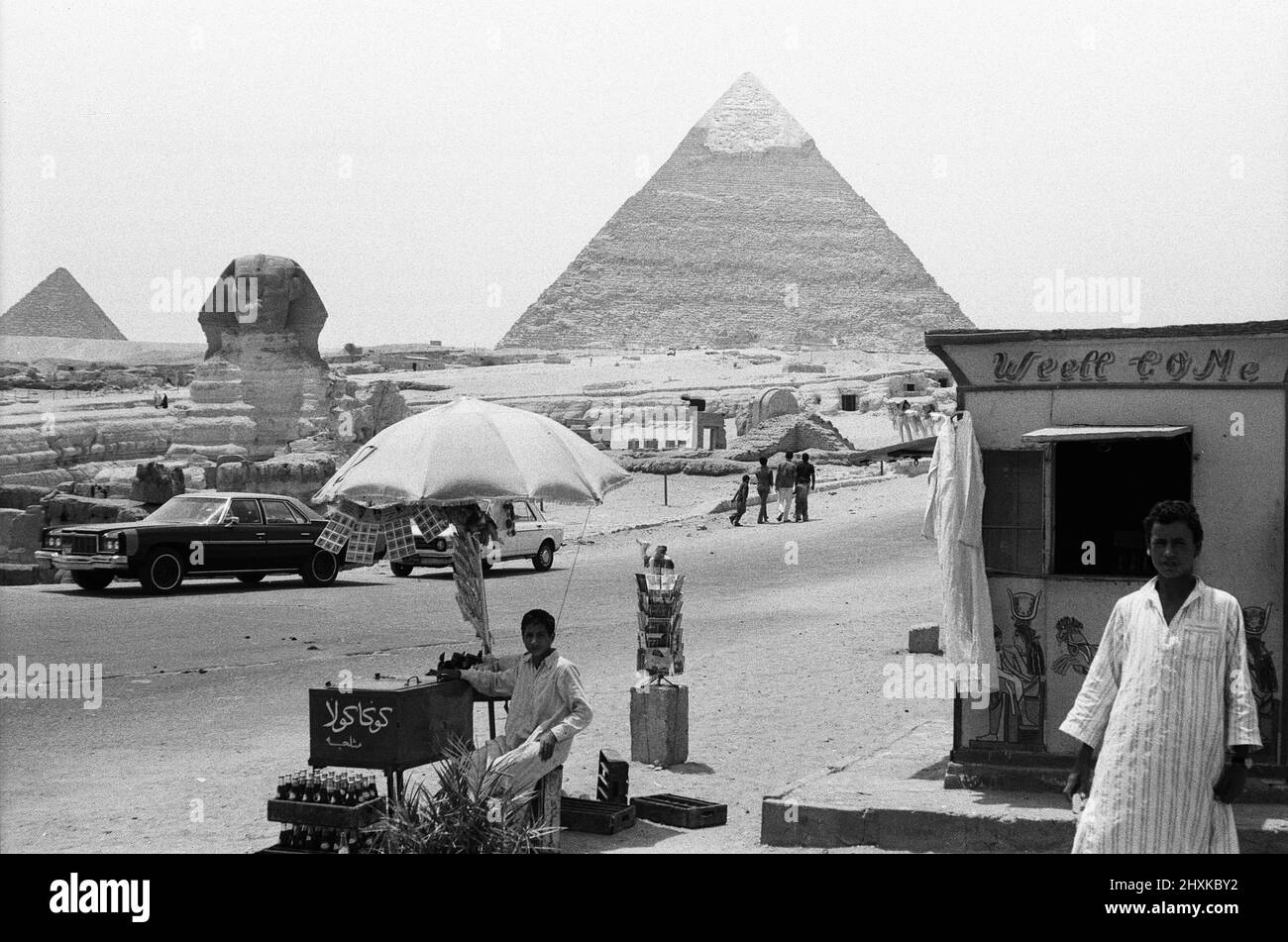 Zwei lokale ägypter, die hier an der Großen Pyramide und Sphinx von Gizeh gesehen wurden, verkaufen Postkarten und Cola an Touristen 29.. Mai 1976 Stockfoto