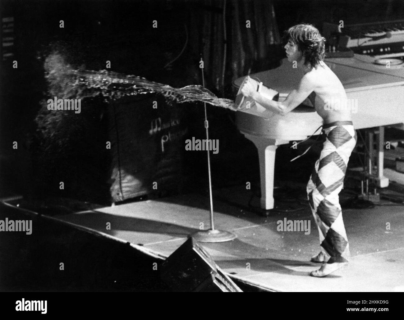 Cool It Man! Die Stones sind zurück: Rockkönig Mick Jagger und seine Rolling Stones sind am Montagabend nach Großbritannien zurückgekehrt. Und 3.500 Fans brauchten bei ihrem ersten Konzerttermin kein Aufwärmen. Rolling Stone Mick Jagger wirft Wasser über die Fans. Mai 1976 P029687 Stockfoto