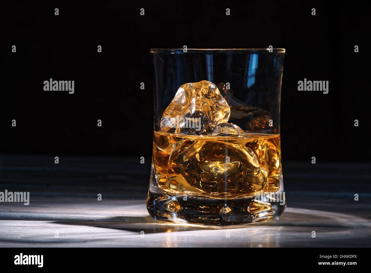 Ein Glas bernsteinfarbenem Scotch-Whiskey und Eis auf dunklem Hintergrund Stockfoto