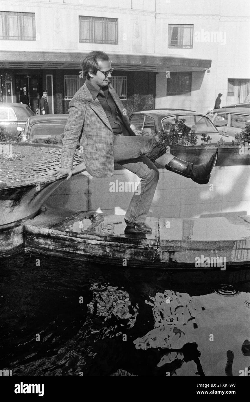 Jack Nicholson posiert vor dem Dorchester Hotel für Fotografen, um für seinen neuen Film „One flog über das Kuckuckennest“ zu werben. Während eines Gesprächs mit Fotografen stolperte Jack zufällig in den Teich. Als er von Fotografen gefragt wurde, es erneut zu tun, weigerte er sich lachend und sagte: „Würden Sie Sir Laurence Olivier bitten, es noch einmal zu tun?“ Aber er hat seinen Stiefel mit Wasser geleert. 9.. Februar 1976. Stockfoto