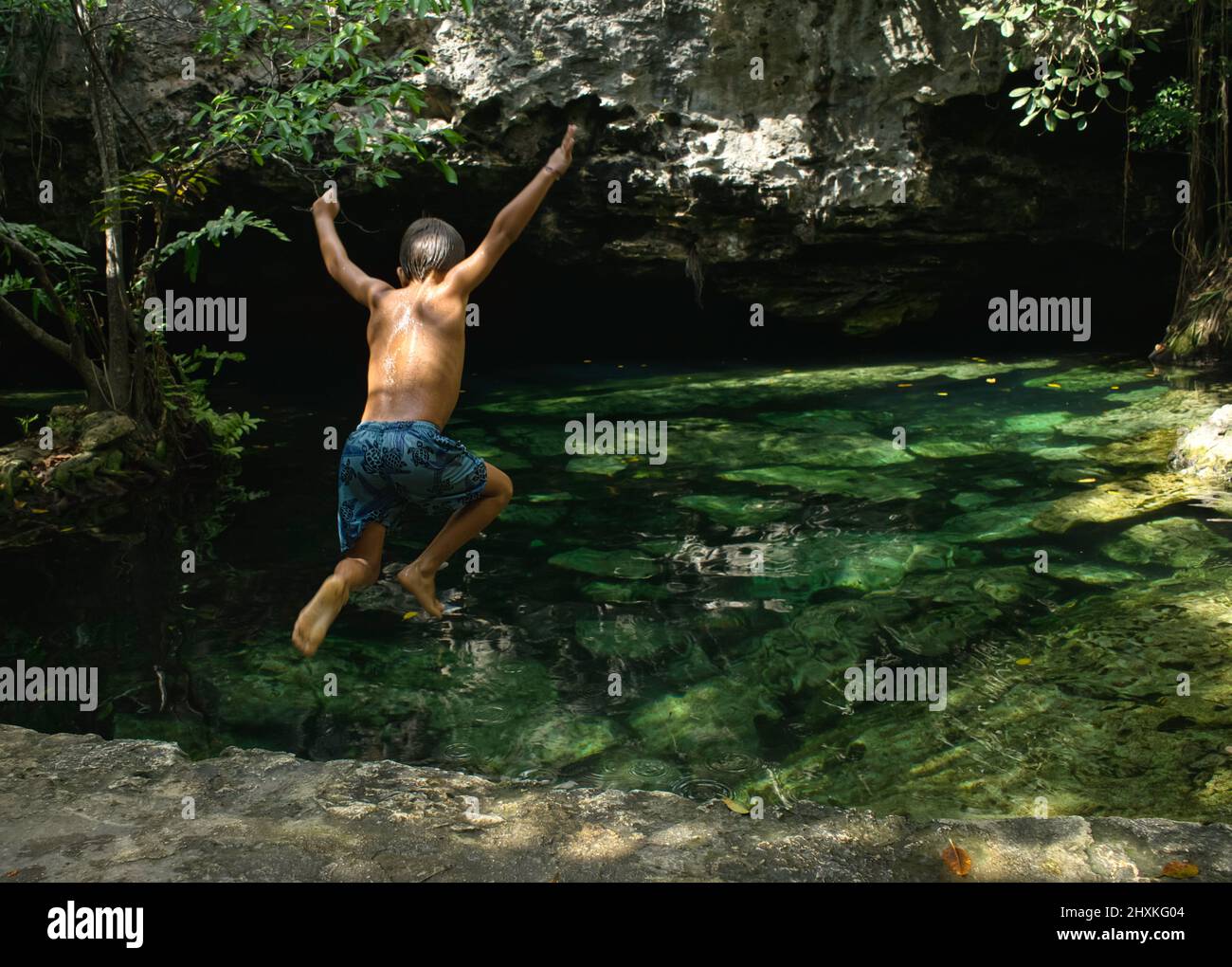Rückansicht eines mexikanischen Teenagers, der im Wald in Mexiko in eine Cenote springt Stockfoto