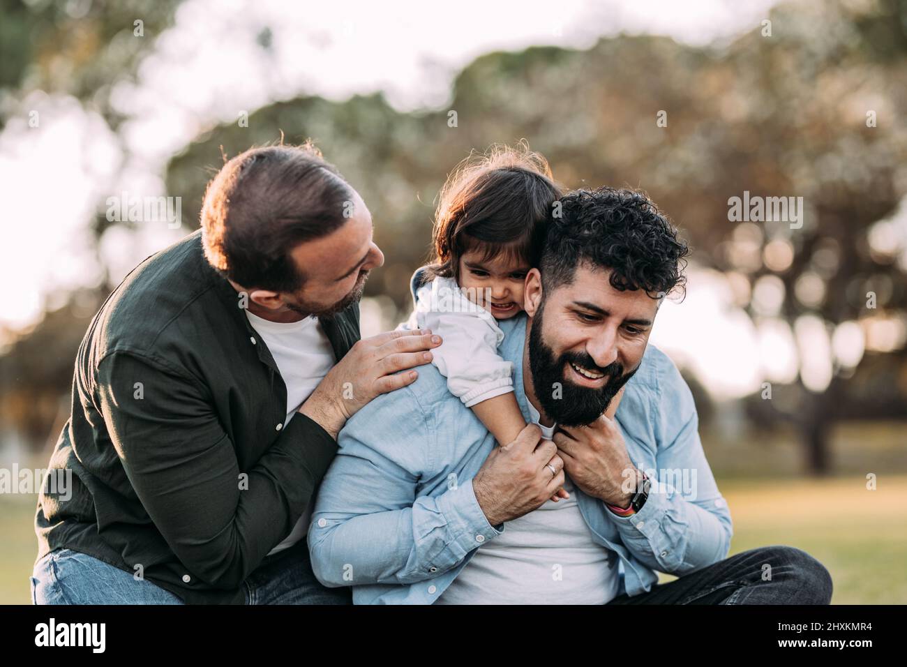 Schwule Eltern genießen mit ihrem Mädchen in einem Stadtpark. Stolze homosexuelle Familienkonzept. Stockfoto