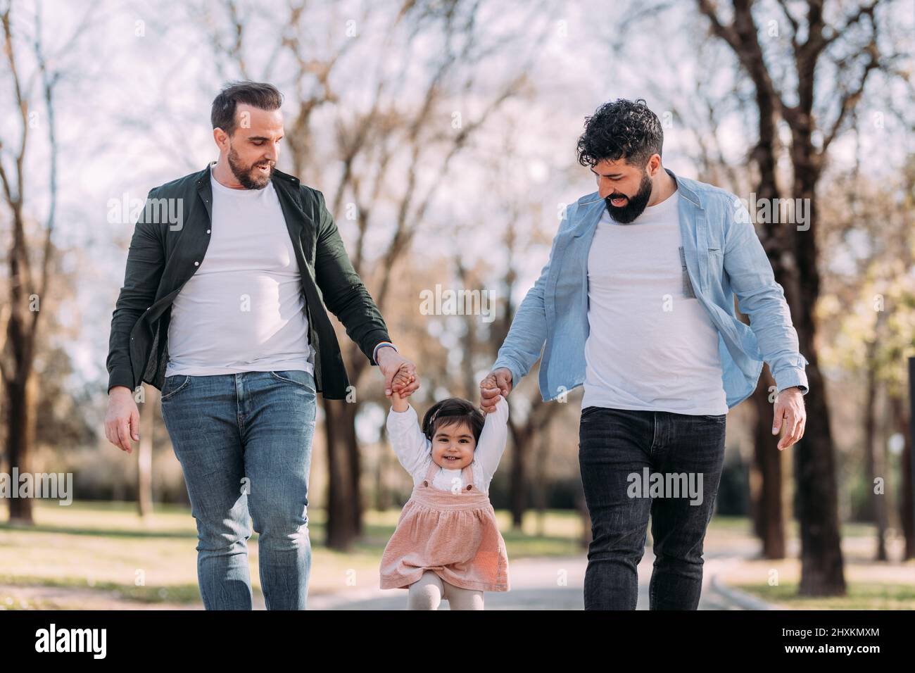 Gay pärchen spielend mit ihre Tochter im die Park. Ein Mädchen mit zwei Vätern Stockfoto