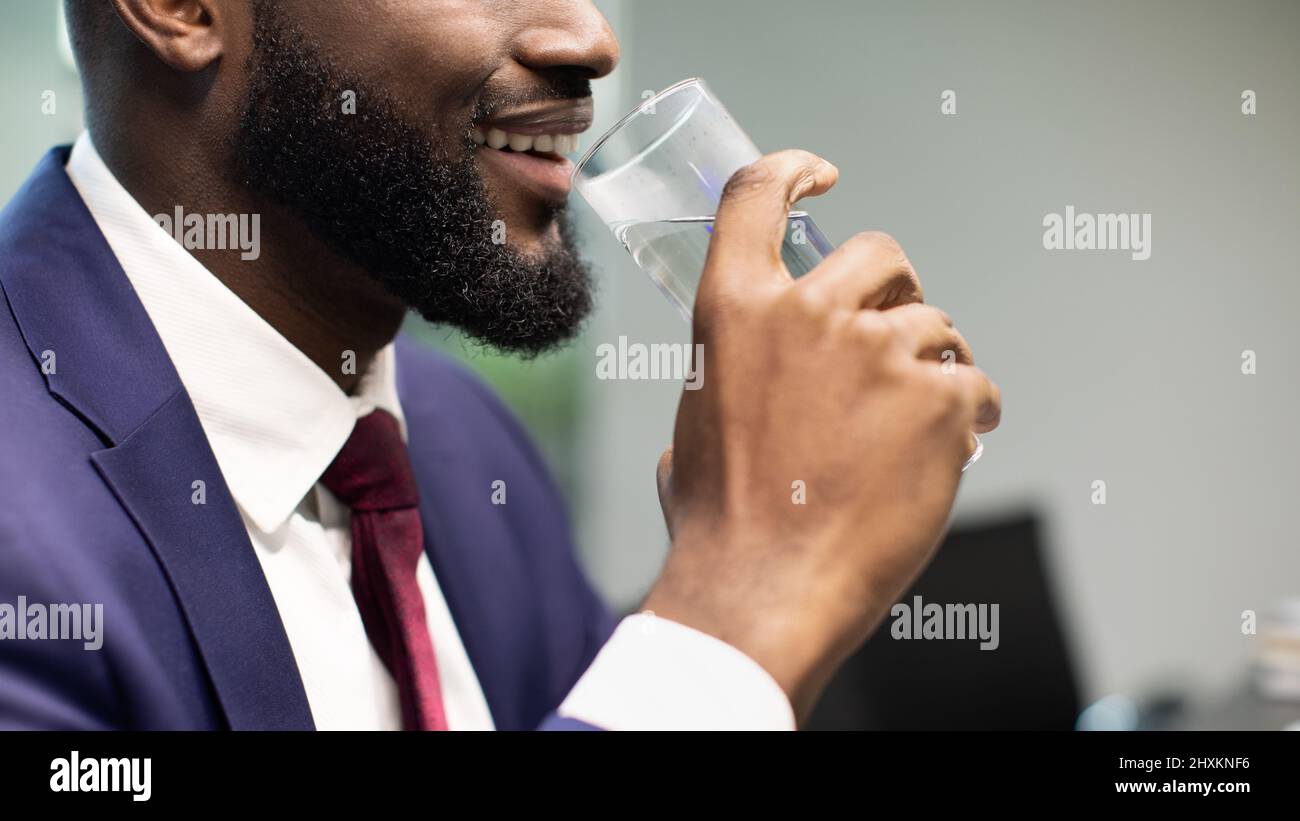 Nicht erkennbarer schwarzer Geschäftsmann Trinkwasser, Kopierraum Stockfoto