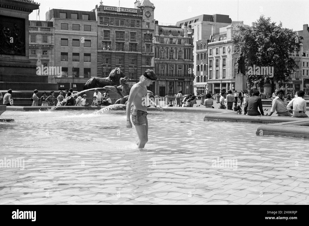 Hitzewelle am Trafalgar Square, London. Als die Temperaturen heute wieder in die 80s Grad aufstiegen, verlockten die kühlen Springbrunnen auf dem Trafalgar Square die Menschen, die um sie herum saßen, noch mehr und inspirierten das Gesetz, das besagt, dass es illegal ist, darin zu baden. 13.. Juni 1976. Stockfoto