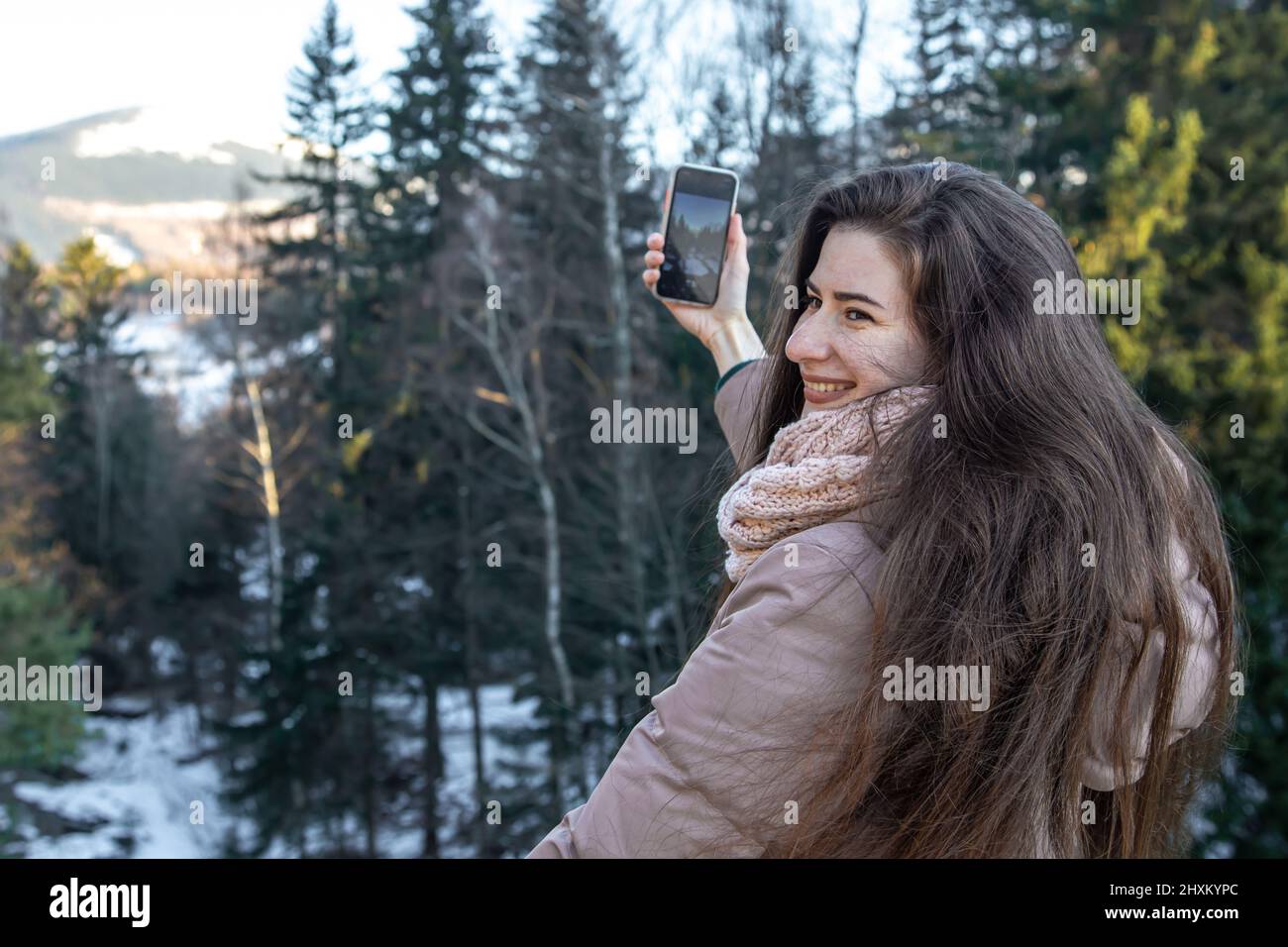 Eine junge Frau fotografiert die Berge mit einem Smartphone. Stockfoto