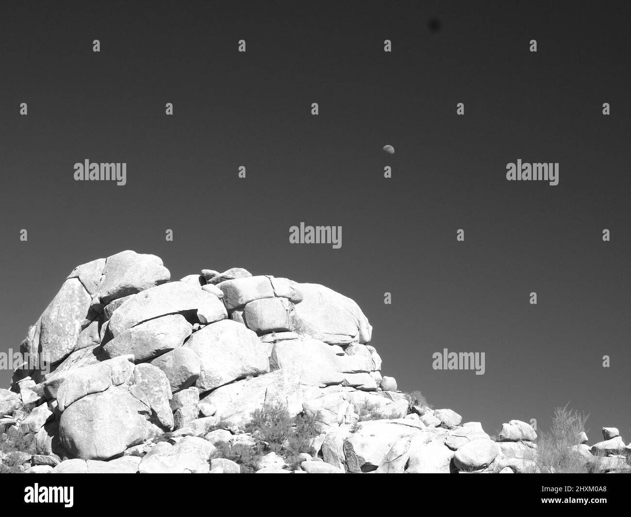 Schwarz-weiße Wüstenlandschaften in Arizona. Gezeigt werden der Superstition Mountain und seine „betende Hände“-Formation sowie ein Mond über dem Wüstenberg. Stockfoto