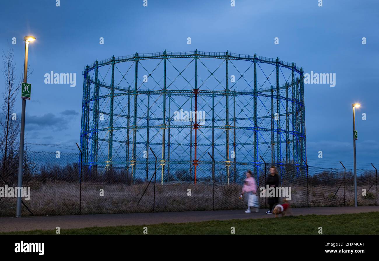 Familie Wanderhund vorbei Granton Gashalter beleuchtet in Solidarität in ukrainischen Farben , Edinburgh, Schottland, Großbritannien Stockfoto