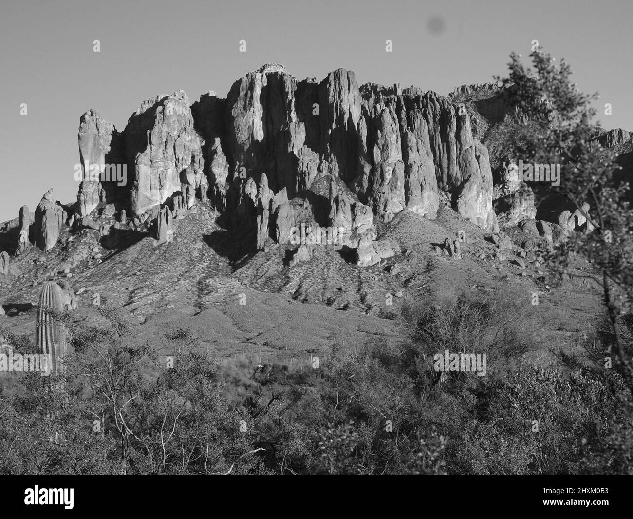 Schwarz-weiße Wüstenlandschaften in Arizona. Gezeigt werden der Superstition Mountain und seine „betende Hände“-Formation sowie ein Mond über dem Wüstenberg. Stockfoto
