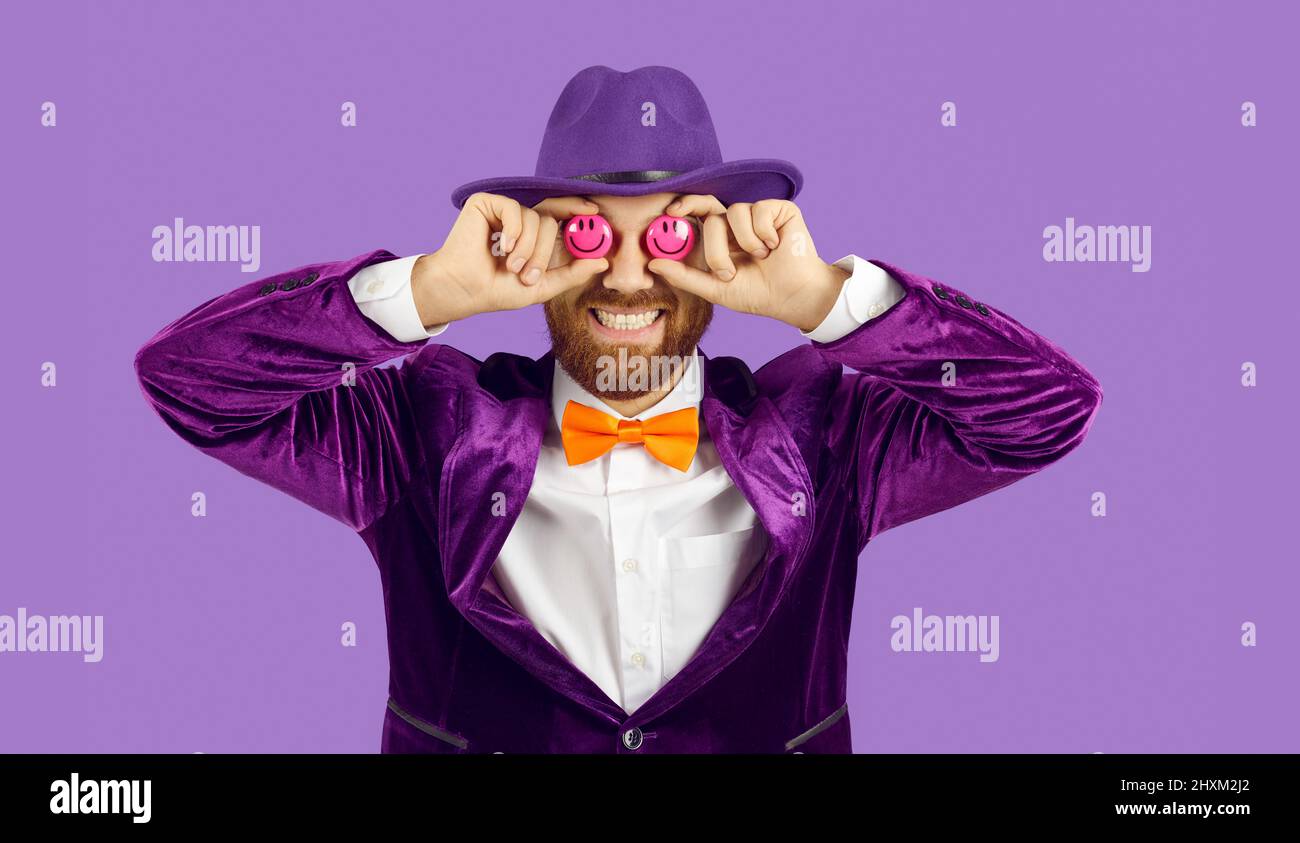 Lustiges Studioporträt eines fröhlichen Mannes, der seine Augen mit zwei Smiley-Emoticons bedeckt Stockfoto