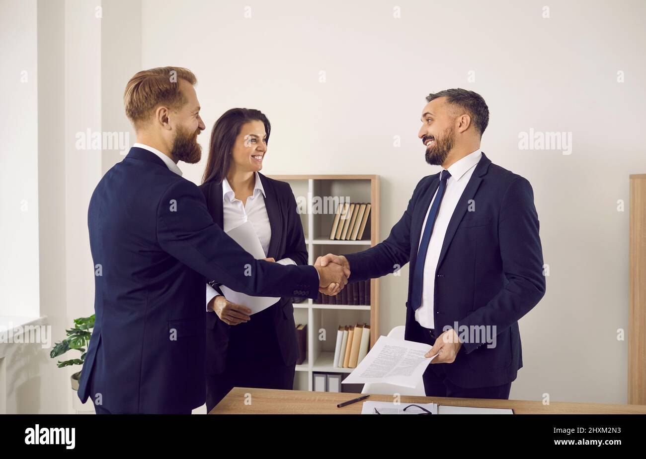 Lächelnde Geschäftsleute geben im Büro den Handschlag, um einen Deal zu schließen Stockfoto