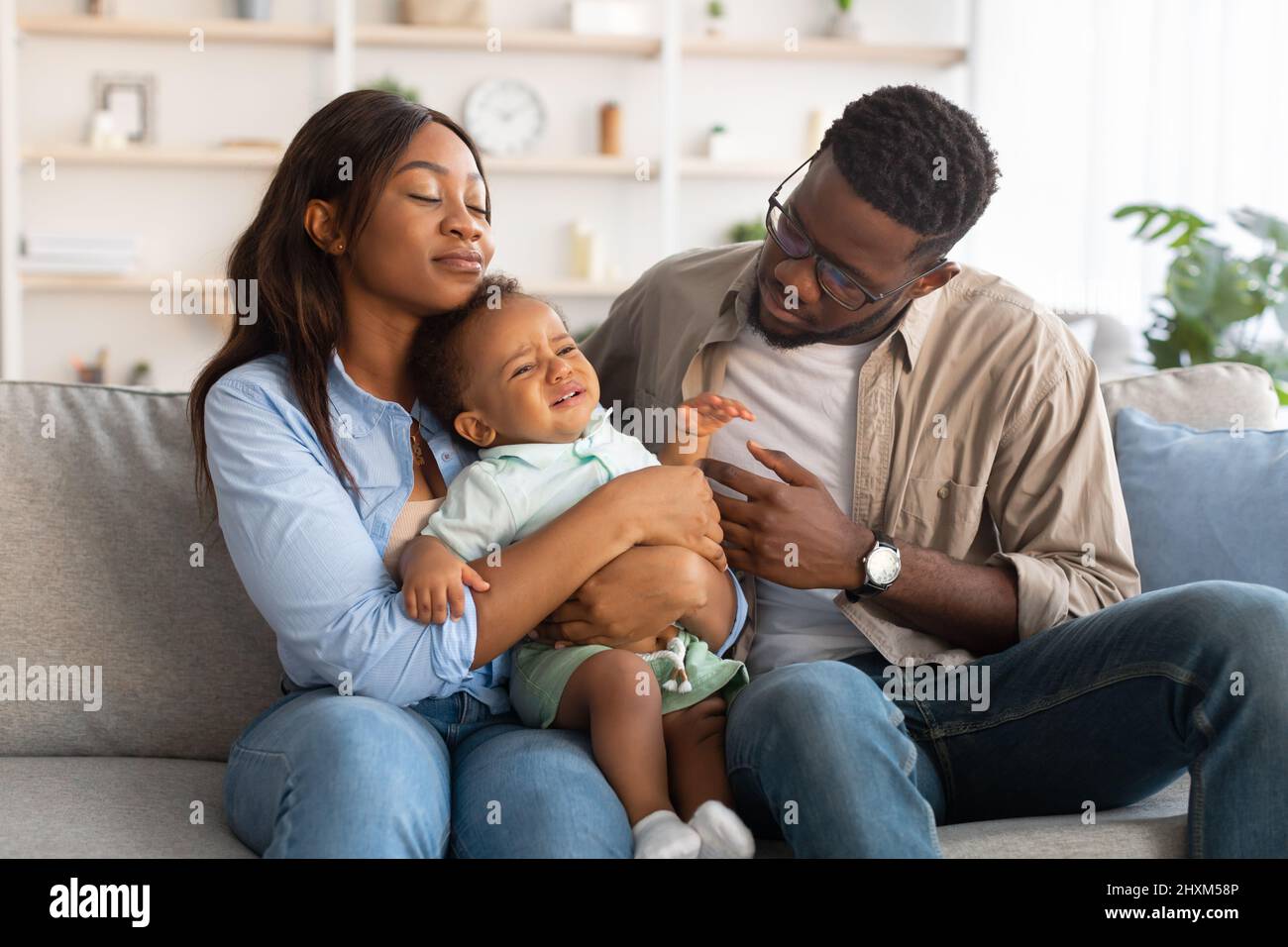 Afroamerikanische Eltern sitzen mit weinenden Jungen auf dem Sofa Stockfoto