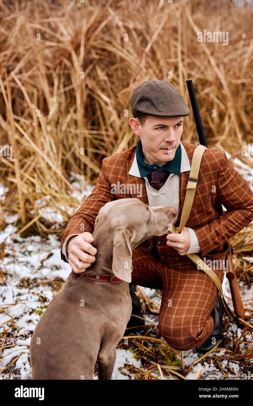 hunter mit Waffe und Weimaraner Hund Rasse Freund in der Natur, sitzen zusammen in der Natur. Erstaunlicher Herbstmorgen, im Freien. Tiere und Menschen Fr. Stockfoto