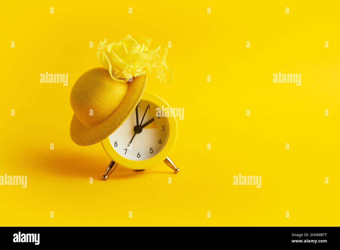 Sommerzeit. Nach vorne springen. Wecker mit Hut auf gelbem Hintergrund Stockfoto