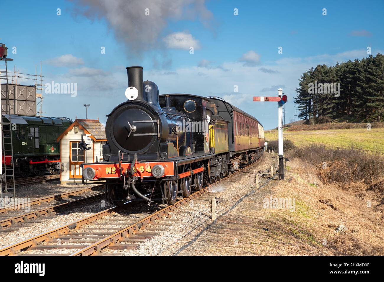 Dampfzug nähert sich an einem blauen Himmel dem Bahnhof der Poppy Line in Weybourne in North Norfolk, Großbritannien Stockfoto