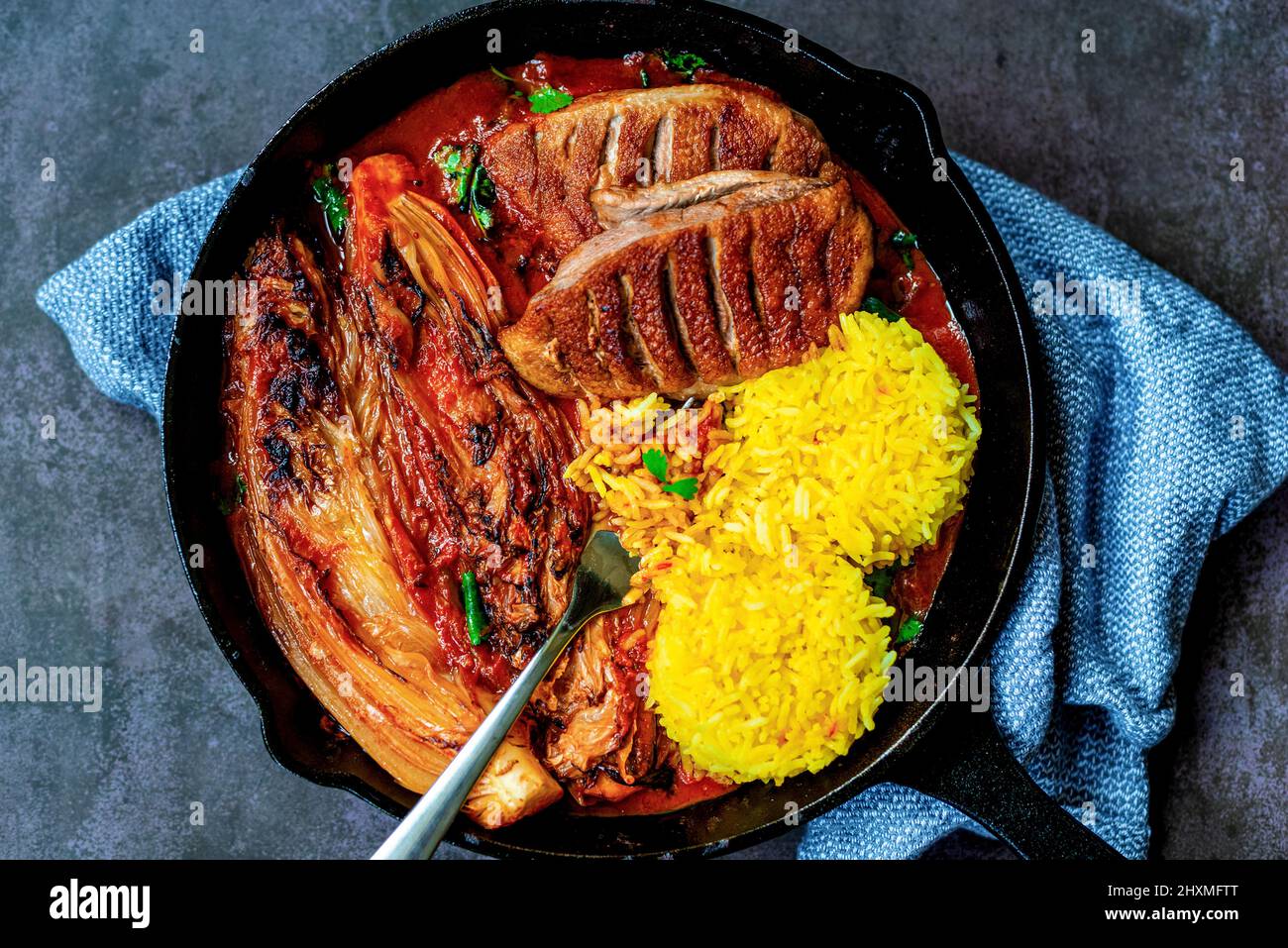 Gegrillte Ente mit napa-Kohl und Safranreis in gusseiserner Pfanne Stockfoto